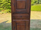 une vieille armoire en bois posée sur une terrasse, à côté d'une pelouse