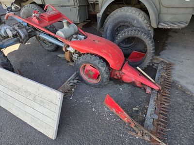 un tracteur rouge garé à côté d'un panneau