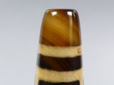 a glass vase that has a brown and black stripe design on it