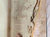 someone is holding an old book open on a white sheet