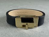 black leather bracelet with a gold buckle on a gray surface