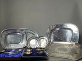 a lot of silver plates and trays sitting on a table