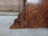a large wooden clock sitting on the floor in front of a wooden door