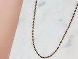 le collier à maillons ronds dorés posé sur une surface en marbre