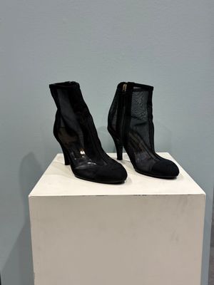 black leather ankle boots with zippers on a white pedestal