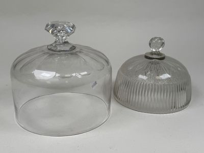 deux bocaux en verre transparent avec leurs couvercles, posés sur une surface blanche