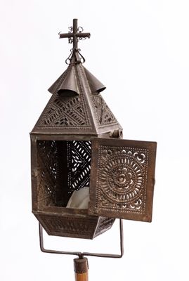 une petite lanterne en métal surmontée d'une croix