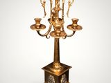 an ornate brass candelab with four candles on a marble base