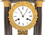 a gold clock with black and white columns and a clock face