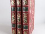 three red books sitting on top of each other on a white surface