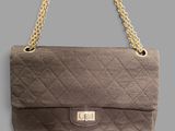 a close up of a purse with a chain on a gray background
