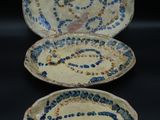 three blue and white plates with designs on them on a black surface