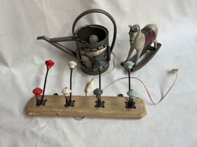 un support en bois sur lequel sont posés un arrosoir, un arrosoir et plusieurs figurines