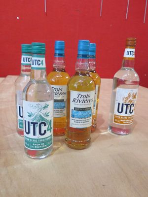 Plusieurs bouteilles d'alcool sont alignées sur une table en bois