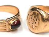 pair of gold rings with garnetts on them on a white surface