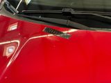 a red car with a sticker on the hood of it