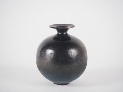 un vase noir posé sur une surface blanche