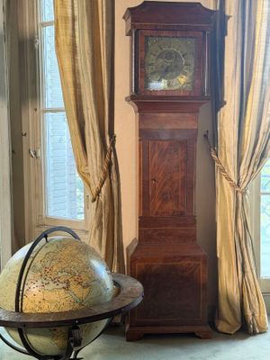 a grandfather clock in the corner of a room with a globe on the floor