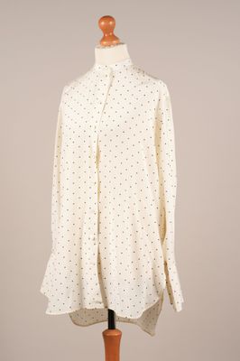 une chemise blanche à pois noirs posée sur un mannequin