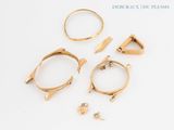 three gold rings and a pair of earrings on a white surface