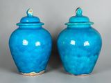 two blue vases with lids are sitting on a gray surface