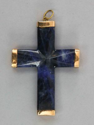 un gros plan d'une croix avec une pierre bleue au centre