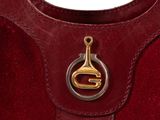 a close up of a red sued handbag with a gold handle