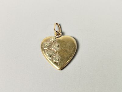 a close up of a gold heart charm on a white surface