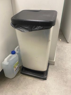 une poubelle posée à côté d'une autre poubelle dans un coin de la pièce