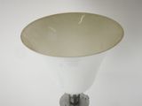 a white vase with a gold rim on a metal stand