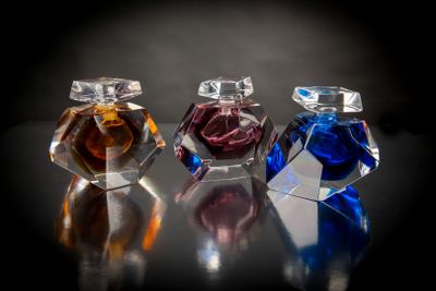 trois flacons de parfum posés sur une table, sur fond noir