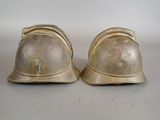 pair of antique brass fire helmets on a white background