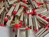 a pile of red and gold lipsticks on a white table