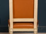 a wooden chair with an orange seat in front of a blue wall