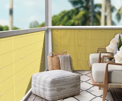 une chaise et un pouf sur un balcon aux murs jaunes