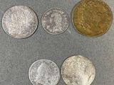 quatre types différents de pièces d'argent et d'or sur une surface grise