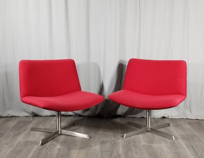 une paire de chaises rouges devant un rideau blanc, sur un parquet