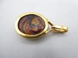 a close up of a gold plated pendant on a white surface