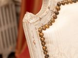 a close up of a white chair with gold beads on it