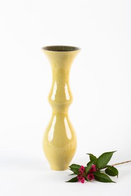un vase jaune avec une fleur sur fond blanc