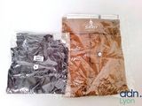 two bags of clothing sitting on a white surface