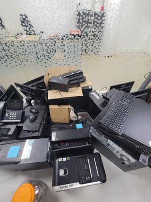 a pile of laptops and other electronic equipment on a table
