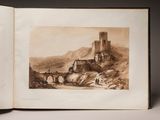 an open book with a drawing of a castle on top of a mountain