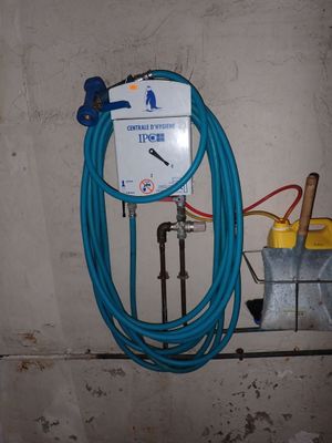 un tuyau raccordé au mur, à côté d'un compteur d'eau