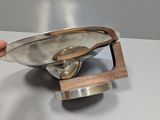 a person that is holding a metal pan on a wooden stand