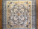 a close up of a square scarf on a wooden floor