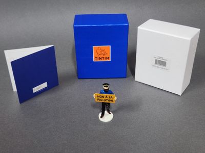 une petite figurine représentant un homme tenant une pancarte à côté d'une boîte
