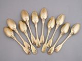 six cuillères en or sont disposées en cercle sur une surface grise