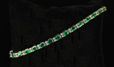 a close up of a green and white bracelet on a black pillow