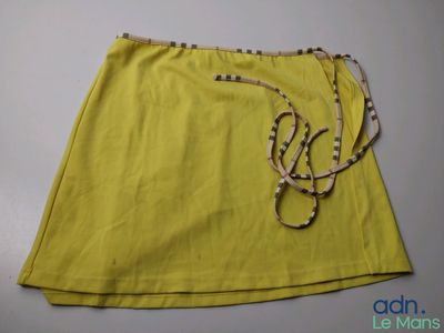 un gros plan d'une jupe jaune posée sur une table blanche
